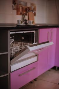 リヴィウにあるOpera Theatre Apartmentsのピンクのオーブン、食器洗い機付きのキッチンが備わります。
