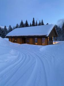 domek pokryty śniegiem z pokrytą śniegiem drogą w obiekcie Stryn Mountain Lodge w mieście Stryn