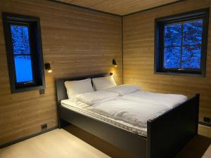 Stryn Mountain Lodge في سترين: سرير صغير في غرفة بها نافذتين