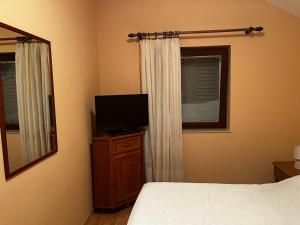 a bedroom with a bed and a tv and a mirror at Apartmani Frakić in Veli Rat
