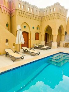 basen z leżakami obok budynku w obiekcie Gold's Villa w mieście Luksor