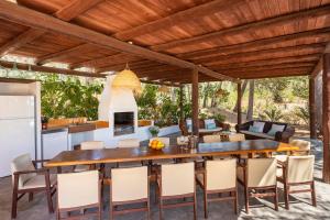 een buitenkeuken en een eetkamer met een houten tafel en stoelen bij Villa Jazmin in Sant Llorenç de Balafia