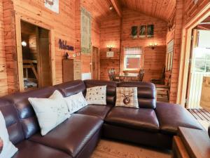 a leather couch in a living room in a log cabin at Gisburn Forest Lodge in Skipton