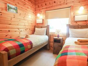 a bedroom with two beds in a log cabin at Gisburn Forest Lodge in Skipton
