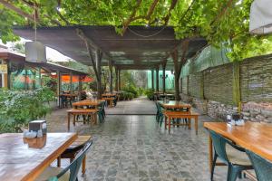 un restaurante con mesas de madera, sillas y árboles en Çıralı Orange Motel, en Cıralı