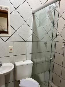 a bathroom with a shower and a toilet and a sink at Pousada da Praia Imbé in Imbé