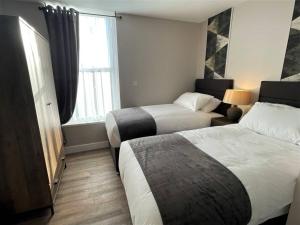 a hotel room with two beds and a window at The Corner Rooms at The Black Horse Inn in Spennymoor