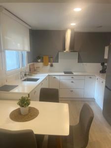 a white kitchen with a table and chairs in it at CONCHEIROS 5 APARTAMENTOS TURISTICOS in Santiago de Compostela