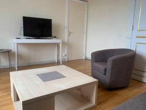 ein Wohnzimmer mit einem Stuhl, einem Tisch und einem TV in der Unterkunft Spacieux Duplex centre Tours et bord du Cher Loire Valley in Tours