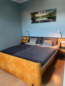 a bed with a wooden frame in a room at FeWo mit 3 SZ, direkte Innenstadtlage, Südterrasse, Parkplatz auf dem eigenem Privatgrundstück, 2x E-Bike und E-Autoladesäule inklusive, Konzertkirche, Schauspielhaus, FH, Jahnsportforum sowie der Tollensesee sind fußläufig in ein paar Minuten erreichbar in Neubrandenburg