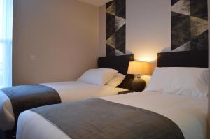 a hotel room with two beds and a lamp at The Corner Rooms at The Black Horse Inn in Spennymoor