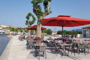 een groep tafels en stoelen met rode parasols bij Chez Gaëlle in Trèbes