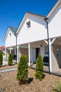 a white house with a porch and some bushes at Domki Scandinavia in Rowy