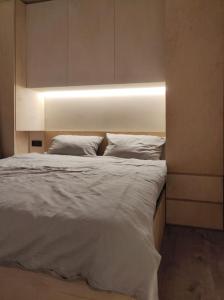 een slaapkamer met een wit bed met een licht erop bij tiny house in Rotterdam