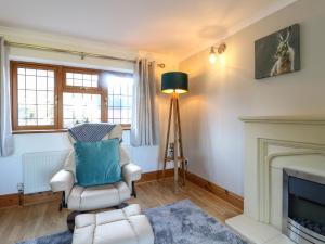a living room with a chair and a fireplace at Adelaide Cottage in Ashbourne