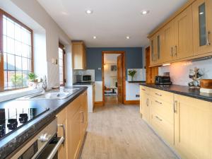 a large kitchen with wooden cabinets and a sink at Adelaide Cottage in Ashbourne