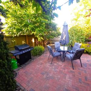 a patio with a table and chairs and a grill at Historic, traditional & Spacious Wiltshire Cottage in Shrewton