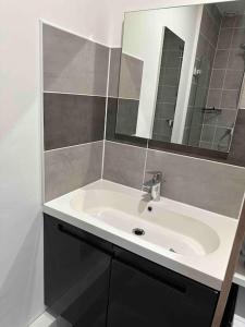 bagno con lavandino bianco e specchio di La Casa de Gaëlle 2 a Trèbes