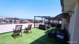 a balcony with chairs and a grill on a roof at Guest house Marina in Obzor