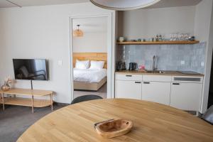 een keuken met een tafel en een slaapkamer met een bed bij Strandhotel Camperduin in Schoorl