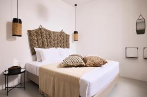a bedroom with a bed with white sheets and pillows at Ianemi Suites by K4 Kythnos in Kithnos