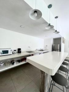 a white kitchen with a white counter and chairs at Residencial Gran Palma in Acapulco