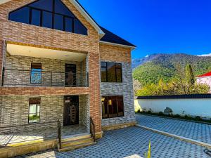 a brick house with a patio and a fence at Gabala Mountain Lodge in Gabala