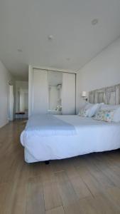 uma grande cama branca num quarto com piso em madeira em Recantus Comporta na Comporta