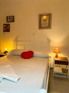 una camera da letto con un letto bianco con un cuscino rosso di Aegean breeze apartment a Karpathos