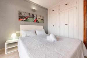 a bedroom with a white bed with a painting on the wall at Aimar Atico duplex Playa la Pineda Port Aventura in La Pineda