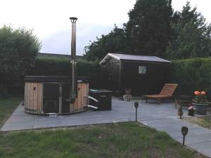 un patio trasero con barbacoa y banco en Wellness - Vildmarksbad og “shelter”, en Sabro