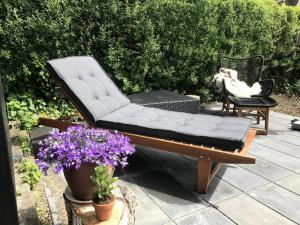 a couch and a chair on a patio with flowers at Wellness - Vildmarksbad og “shelter” in Sabro