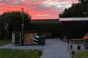 una puesta de sol en un patio trasero con una mesa y una silla en Wellness - Vildmarksbad og “shelter”, en Sabro