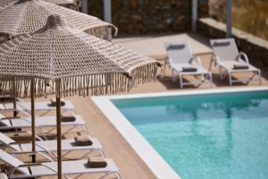 a group of chairs and umbrellas next to a pool at Ianemi Suites by K4 Kythnos in Kithnos