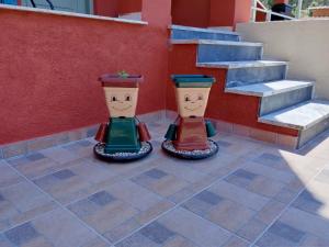 dwie wazy z malowanymi twarzami siedzące obok schodów w obiekcie maria corfu apartments w mieście Mesongi