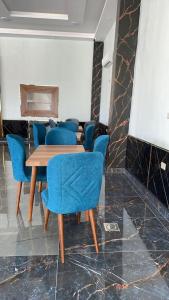 een eetkamer met blauwe stoelen en een houten tafel bij اوركيدا الشمال للشقق الفندقية in Al Mafraq