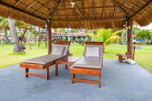 two chairs and a bench under a straw umbrella at Sítio Praia dos Carneiros in Tamandaré