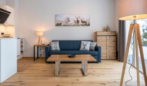 ein Wohnzimmer mit einem blauen Sofa und einem Tisch in der Unterkunft Hotel Residenz Hochalm in Saalbach-Hinterglemm