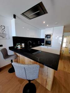 cocina con encimera negra y 2 sillas en Luxury Apartment La Mata right by the sea, en La Mata