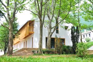 una casa bianca con degli alberi di fronte di Youth Hostel Ajdovscina a Ajdovščina