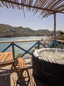 una bañera de hidromasaje y una silla en una terraza junto al agua en GLAMPING BAReKE AZUL2 en Santa Marta