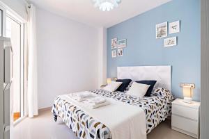 a white bedroom with blue walls and a bed at Elegante piso en la Romanilla in Roquetas de Mar