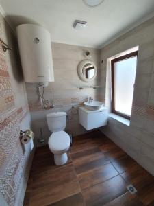 a bathroom with a toilet and a sink and a window at Стаи за гости Елеганс in Elena