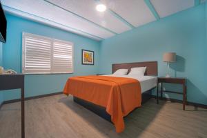 a bedroom with a bed with an orange blanket on it at NOHO Hotel near Universal Studios Hollywood in Los Angeles