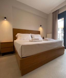 a bedroom with a large bed with white sheets and a window at Toumba apartments in Thessaloniki