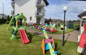 a playground with colorful equipment in the grass at Barka Pokoje i Apartamenty in Karwia