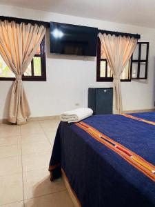 a bedroom with a blue bed and two windows at El Bosque Hotel in Copan Ruinas