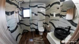 a bathroom with a toilet and a black sink at Stream House - Luxury living next to the river in Samothráki