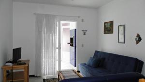 sala de estar con sofá azul y puerta corredera de cristal en 1031 - Apartamento para locação em Bombinhas - Residencial Solar das Bromélias Apto 157, en Bombinhas