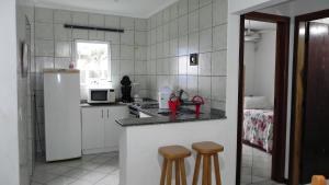 una pequeña cocina con nevera y 2 taburetes en 1031 - Apartamento para locação em Bombinhas - Residencial Solar das Bromélias Apto 157, en Bombinhas